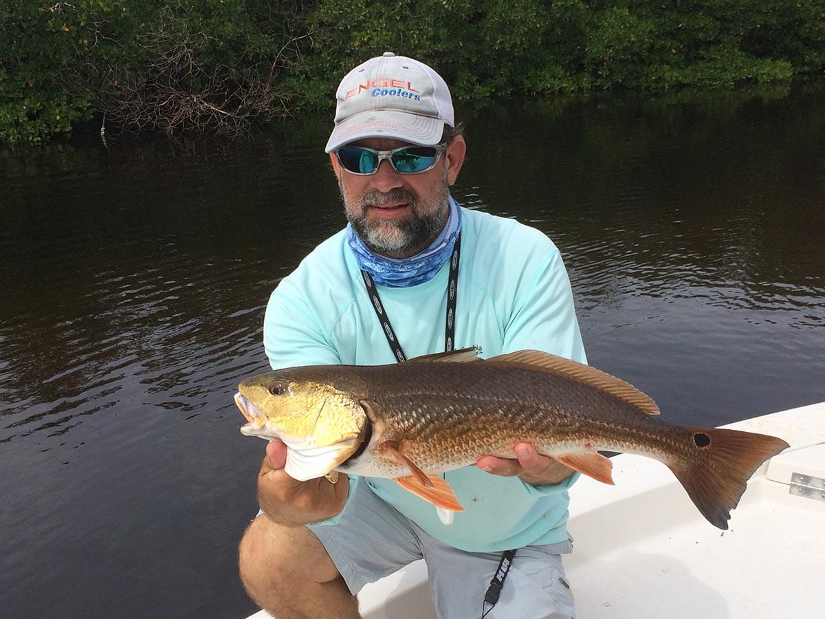 a fisherman with a naples redfish